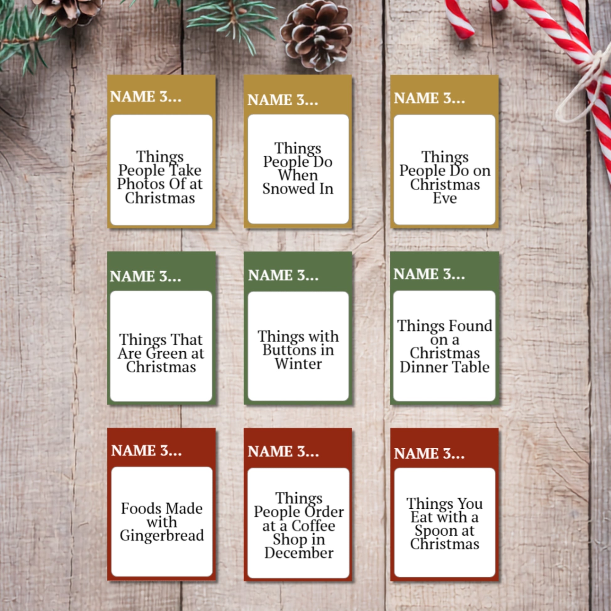 Nine Christmas-themed name cards arranged in a 3x3 grid on a rustic wooden background, decorated with pine branches, a pinecone, and a candy cane. Each card has a different holiday color header (gold, green, or red) and a white text box with customizable prompts like 'Things People Take Photos Of at Christmas' and 'Foods Made with Gingerbread'.